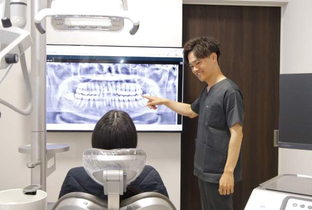 鏡に映った自分の歯を心配そうに見つめる女性