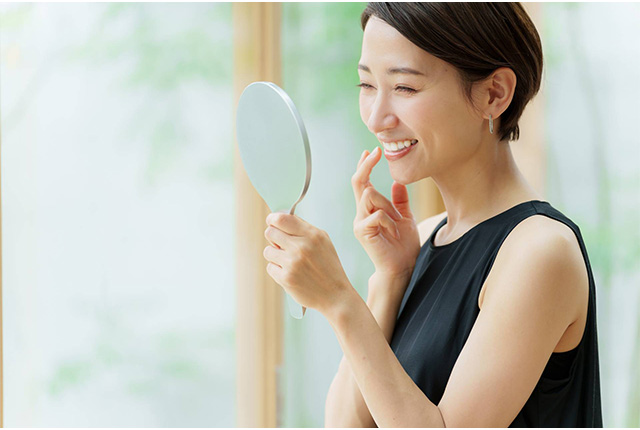 歯を見せて鏡を見て微笑む女性